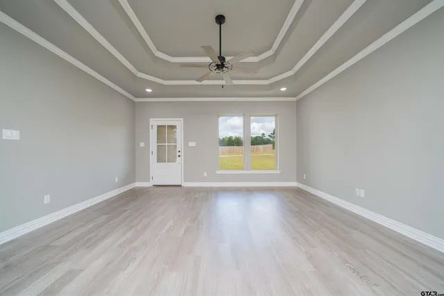 a view of an empty room with a window and wooden floor