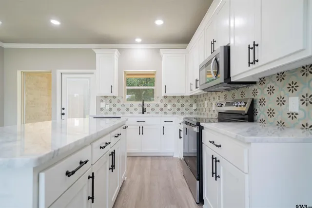 a kitchen with granite countertop a sink stove and cabinets