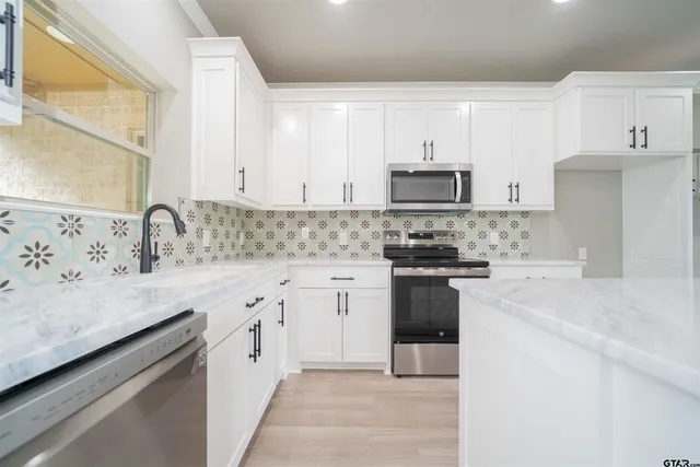 a kitchen with granite countertop white cabinets and stainless steel appliances