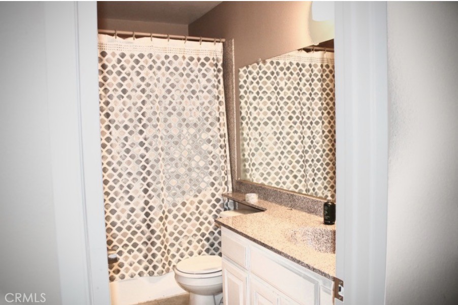 25584 Sharp Drive, Unit D Hemet, CA 92544 - Photo 7 of 9 a bathroom with a granite countertop toilet and a shower curtain