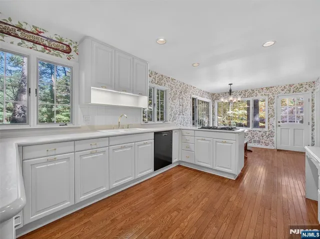 a large white kitchen with a large window a sink and cabinets