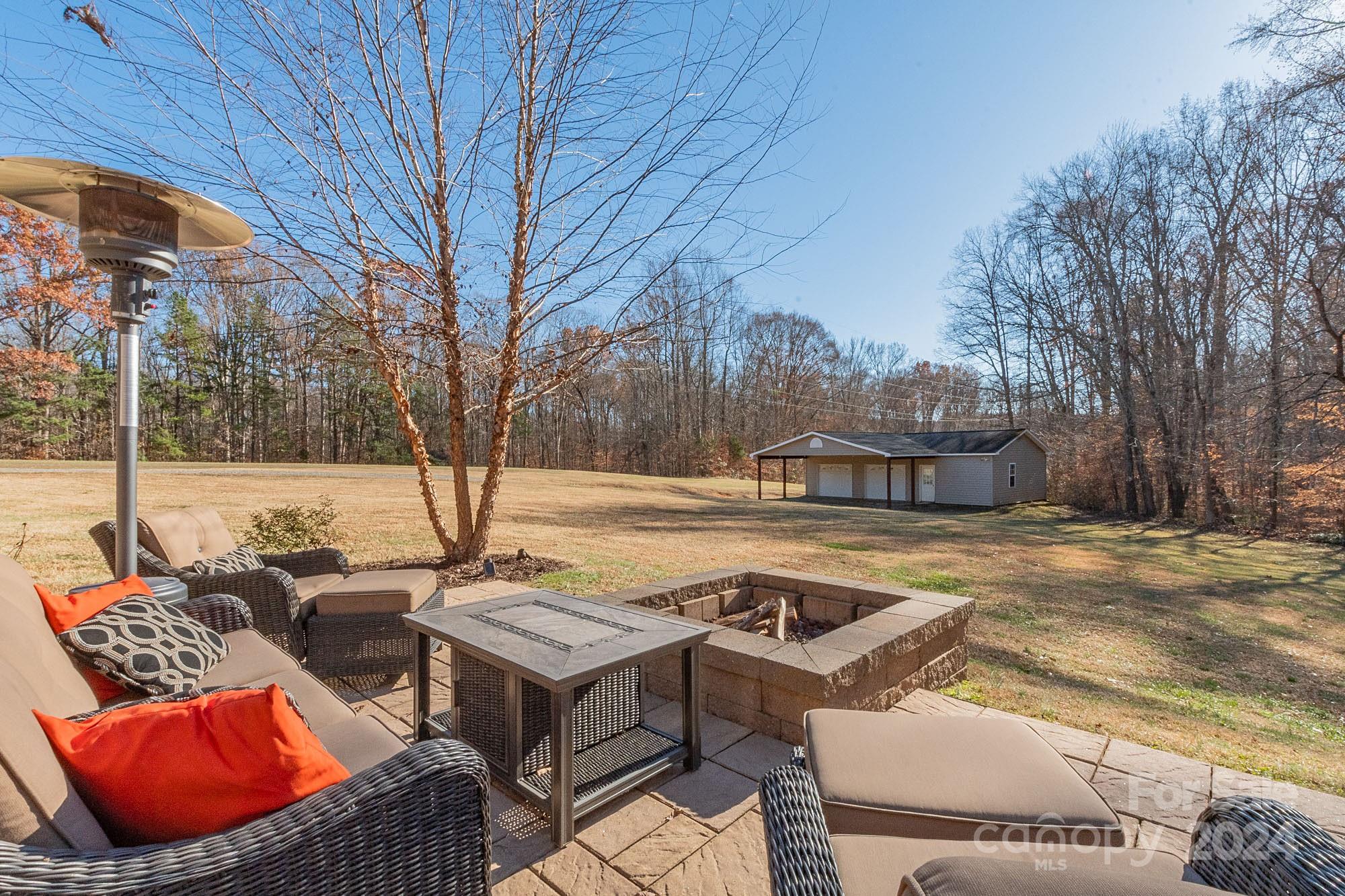 3211 Happy Hill Road Lexington, NC 27295 - Photo 38 of 44 a view of a patio with couches and table and chairs under an umbrella with large trees