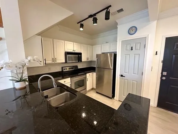 a kitchen with stainless steel appliances granite countertop a refrigerator a microwave a sink and wooden floor