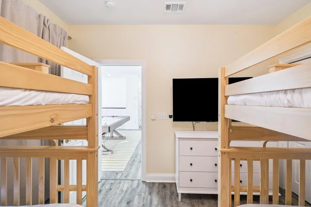 a kitchen with stainless steel appliances a dining table chairs wooden floor and a refrigerator