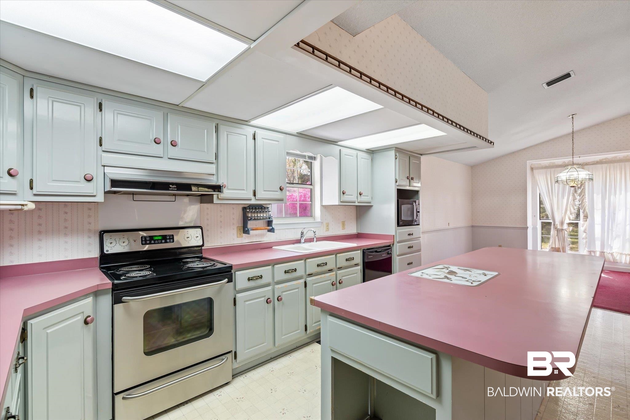 6030 Lott Road Eight Mile, AL 36613 - Photo 6 of 21 Kitchen featuring wallpapered walls, light floors, under cabinet range hood, a wealth of natural light, and black appliances