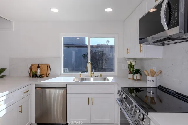 a kitchen with a sink dishwasher and white cabinets with wooden floor