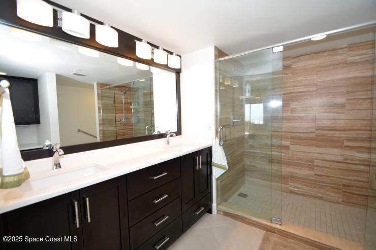 8700 Ridgewood Avenue, Unit B310 Cape Canaveral, FL 32920 - Photo 17 of 23 a bathroom with a shower sink and mirror