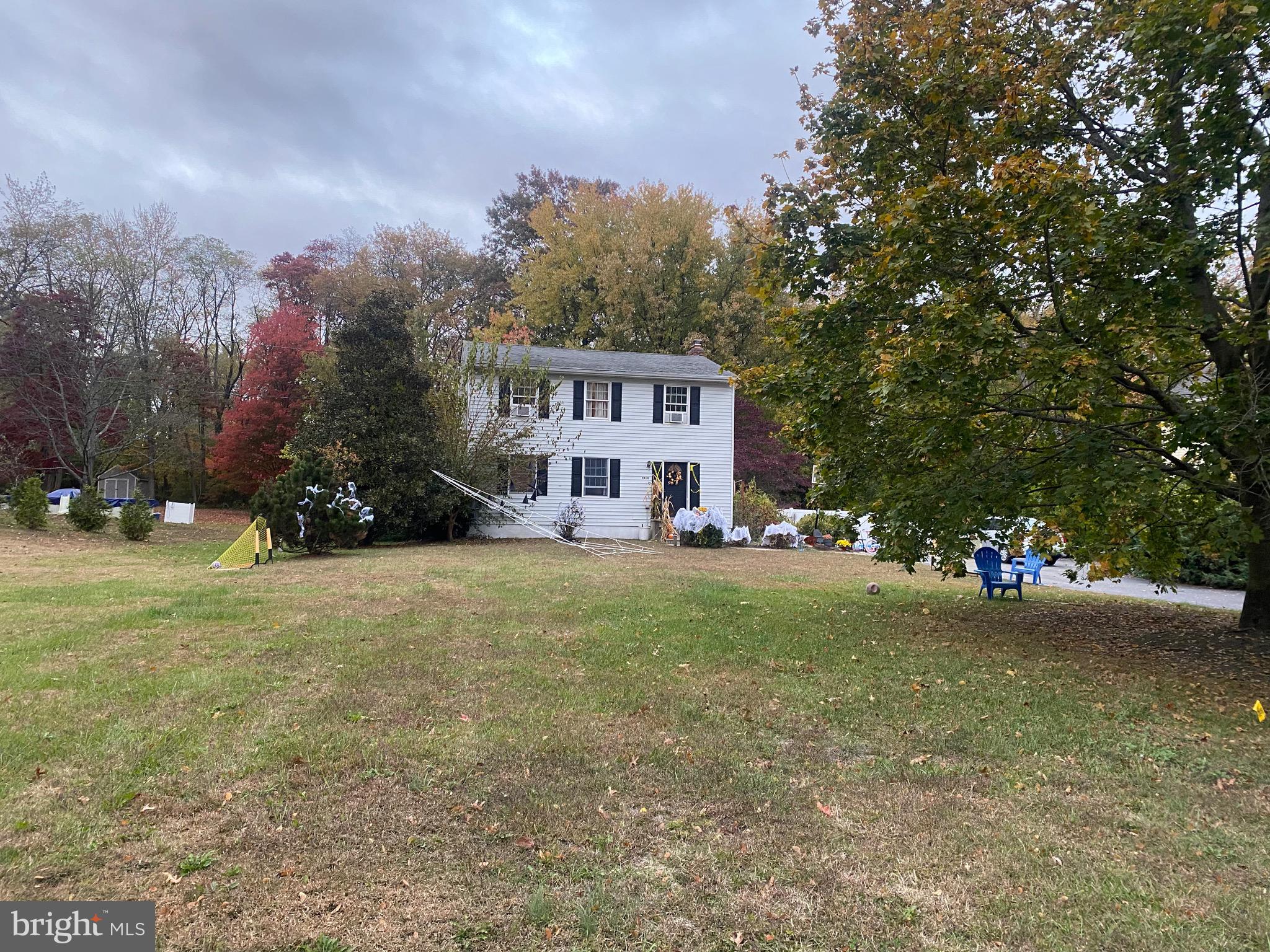 a view of a house with a yard and large trees