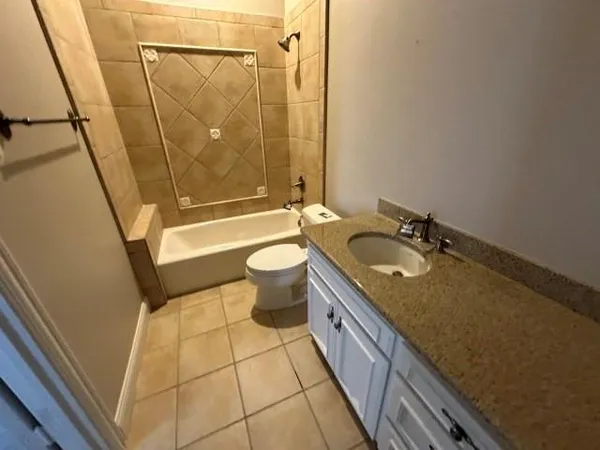 an empty room with wooden floor ceiling fan and kitchen view