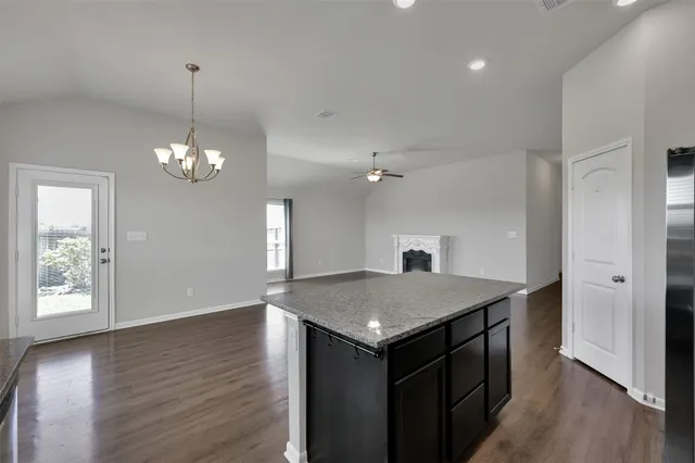 a kitchen with stainless steel appliances granite countertop a refrigerator a sink dishwasher a stove and a dining table with wooden floor