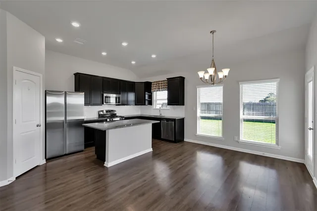 a kitchen with stainless steel appliances granite countertop a sink a stove a refrigerator and a microwave