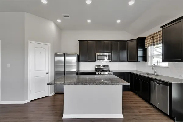 a kitchen with stainless steel appliances granite countertop a stove a sink and a refrigerator