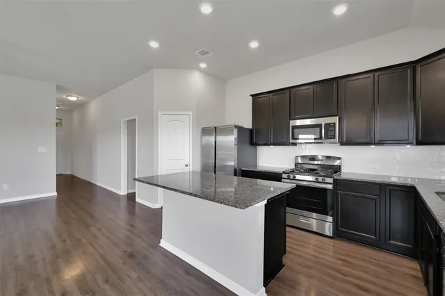 a kitchen with granite countertop a sink dishwasher stove top oven and wooden floor