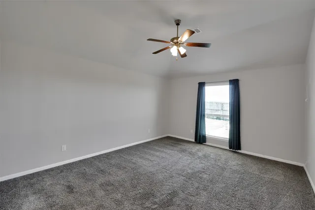 an empty room with chandelier fan and windows