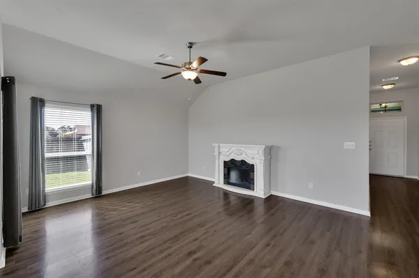a view of an empty room with a fireplace and wooden floor