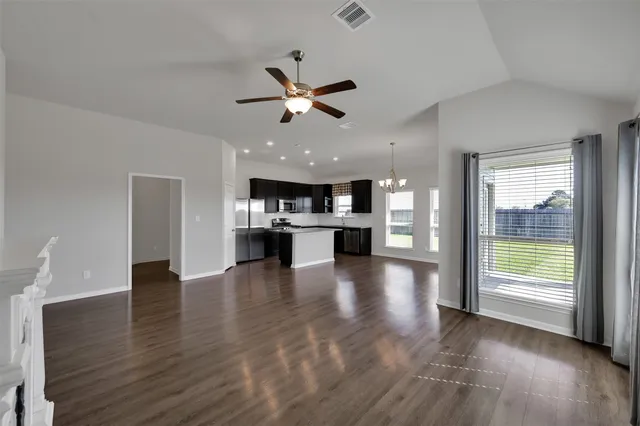 a view of an empty room with kitchen and a window