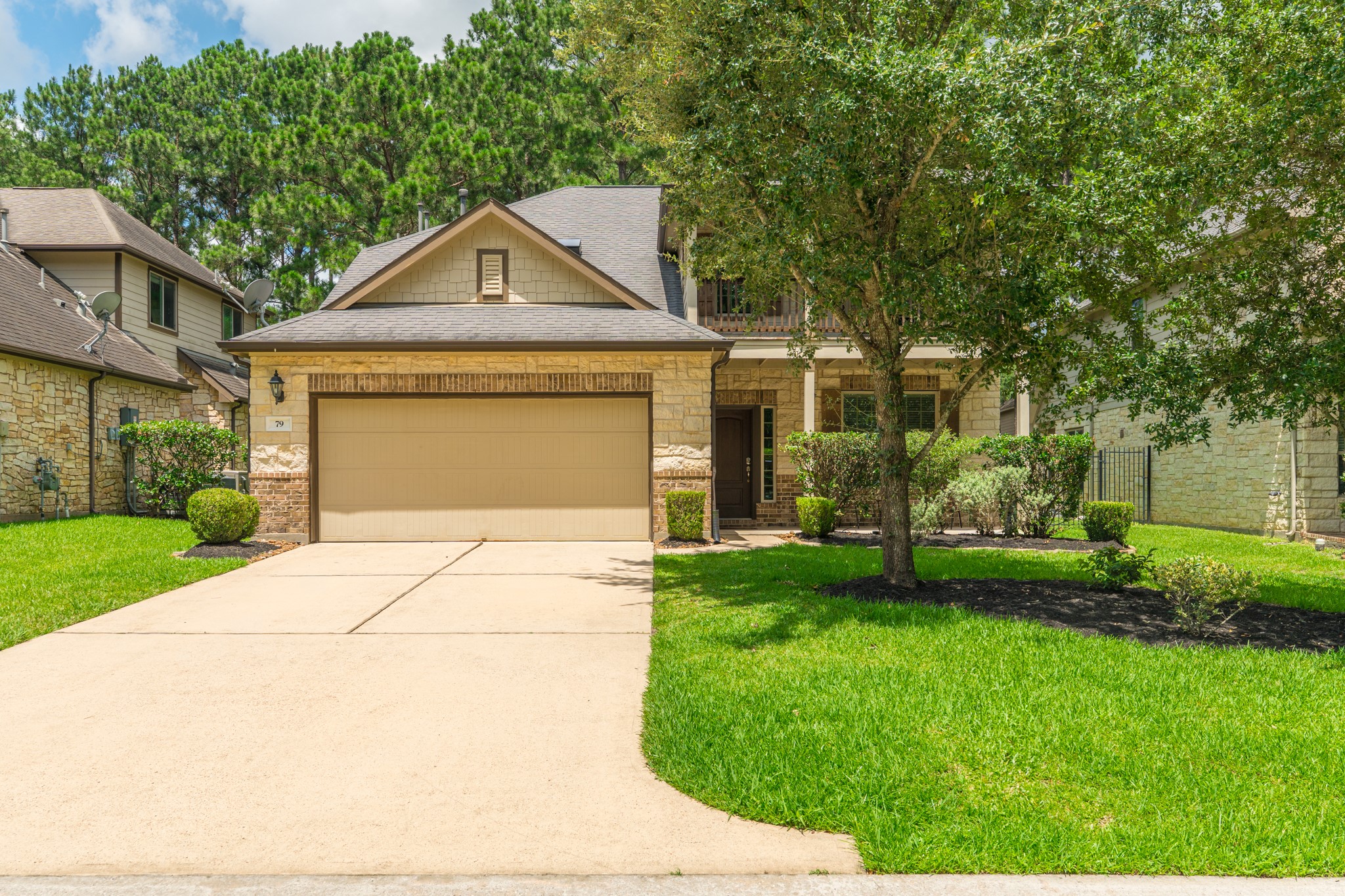 79 West Jagged Ridge Circle Spring, TX 77389 - Photo 5 of 50 This closer view of the front exterior showcases the home's tan and stone facade, covered front porch with classic columns, and beautifully maintained landscaping. The two-car garage and inviting entry create a warm, welcoming first glimpse of everything this home has to offer.