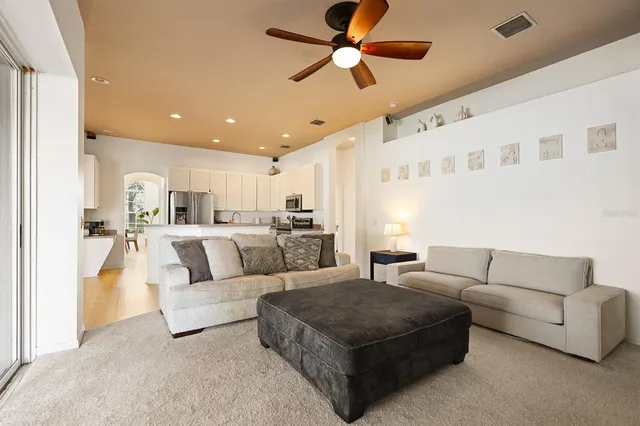 a living room with furniture kitchen view and a chandelier