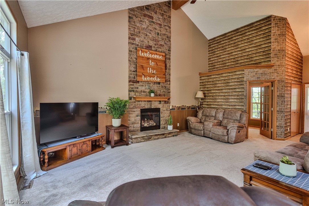 11154 Johnsford Road Southwest Beach City, OH 44608 - Photo 15 of 50 Spacious living area featuring a vaulted ceiling, prominent brick fireplace with stone hearth, and light-toned carpeting