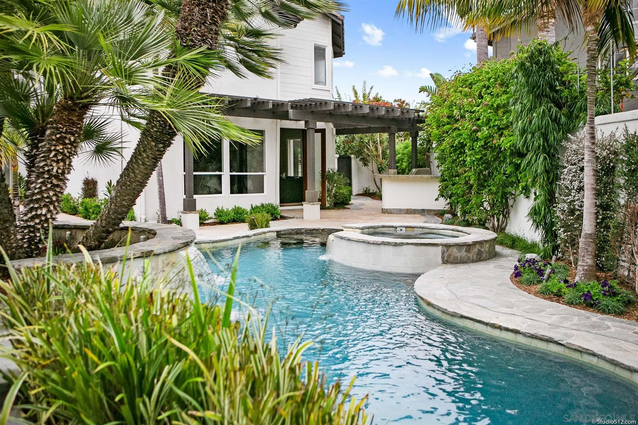 220 Jacob Lane Encinitas, CA 92024 - Photo 37 of 40 a view of a white house with a large pool and table and chairs under an umbrella