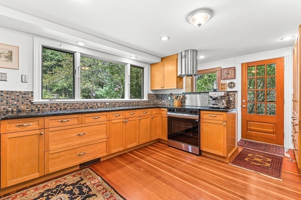 55 Pleasant Street Lexington, MA 02421 - Photo 14 of 42 a kitchen with stainless steel appliances granite countertop a stove a sink and a granite counter tops with white cabinets next to a window