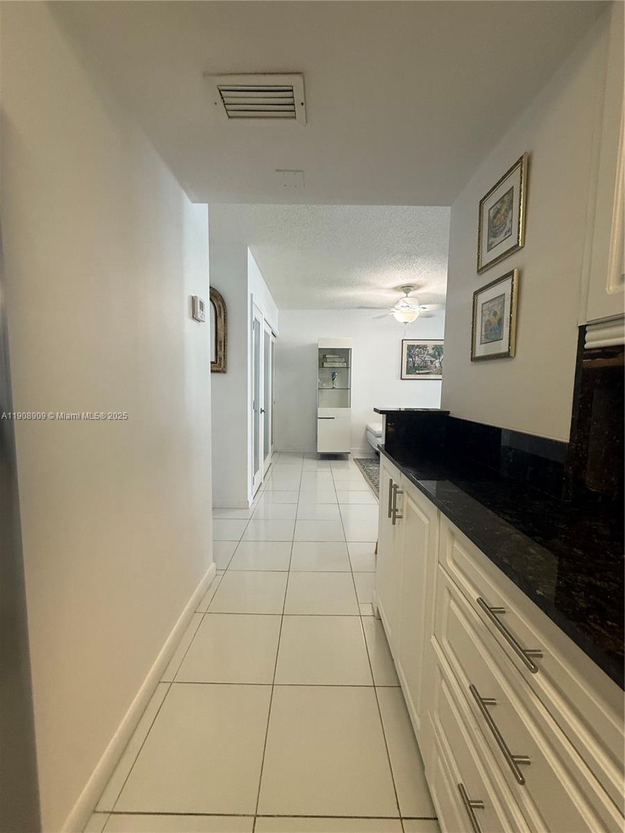 9511 Collins Avenue, Unit 1208 Surfside, FL 33154 - Photo 11 of 37 a large white kitchen with a sink and cabinets