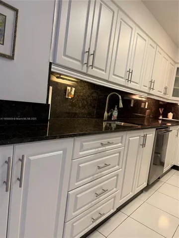 a kitchen with white cabinets and black appliances