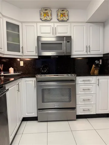 a kitchen with white cabinets and appliances