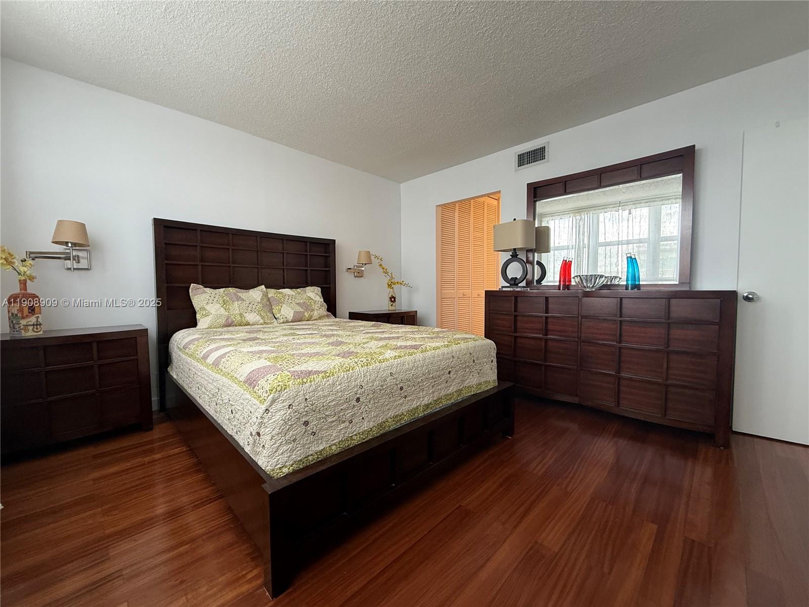9511 Collins Avenue, Unit 1208 Surfside, FL 33154 - Photo 18 of 37 a bedroom with a bed and wooden floor