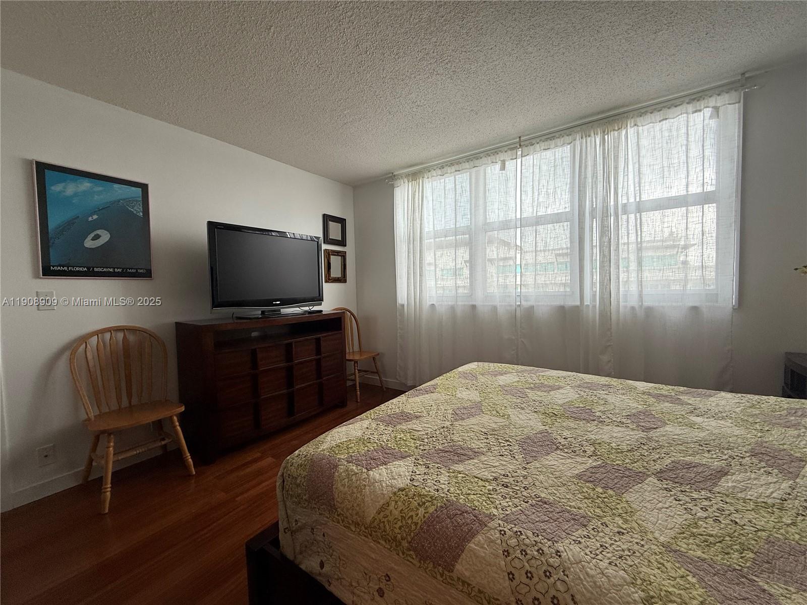 9511 Collins Avenue, Unit 1208 Surfside, FL 33154 - Photo 20 of 37 a bedroom with a bed and a flat screen tv