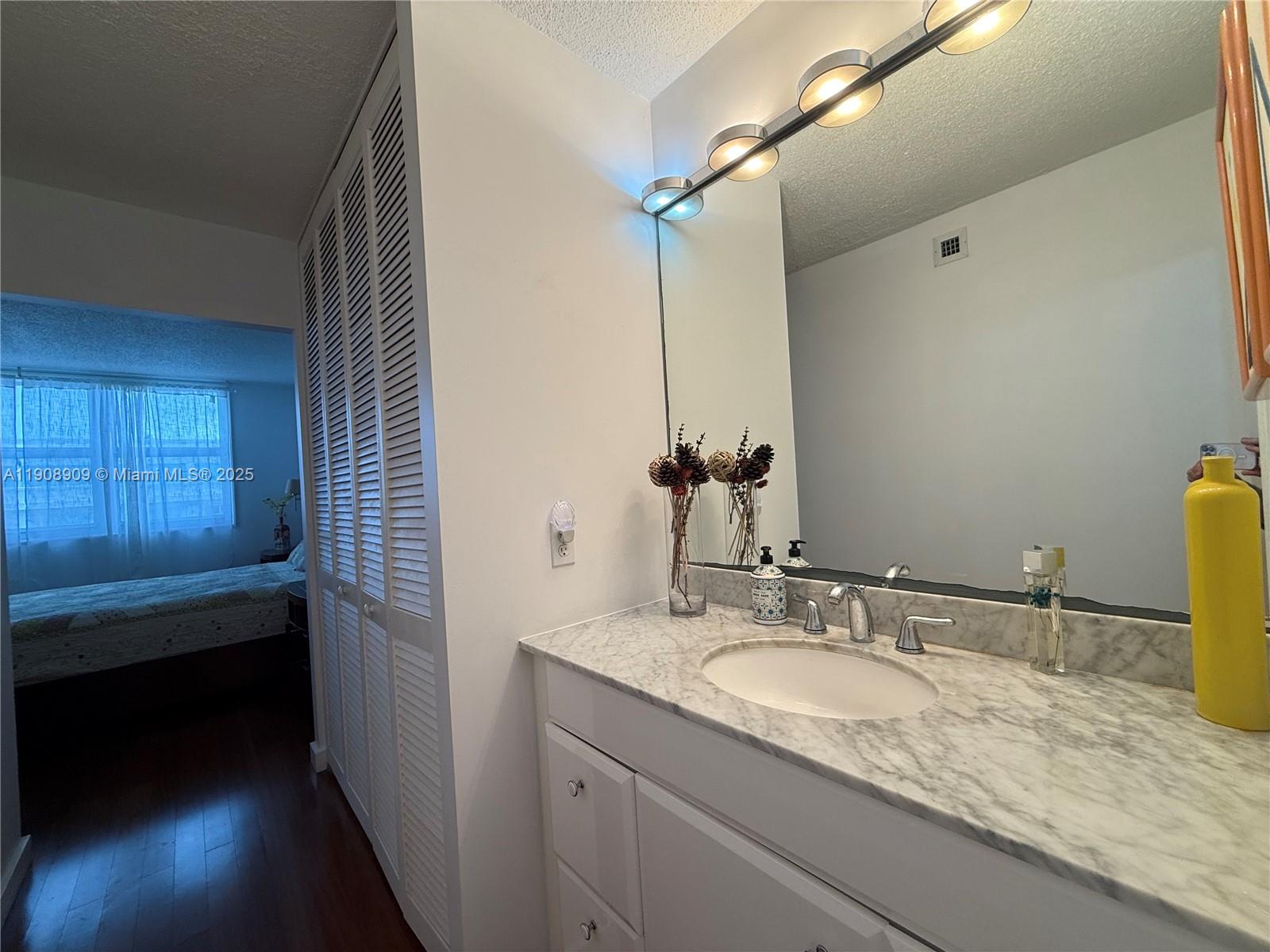9511 Collins Avenue, Unit 1208 Surfside, FL 33154 - Photo 22 of 37 a bathroom with a granite countertop sink and a mirror