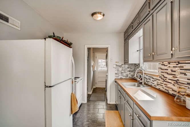 3880 Quay Street Wheat Ridge, CO 80033 - Photo 23 of 32 a kitchen with a refrigerator a sink and cabinets