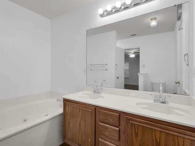 a bathroom with a sink double vanity granite tub and a mirror