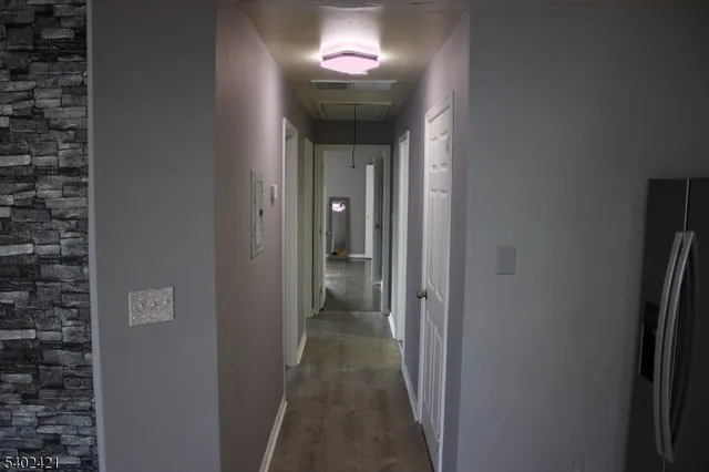 a view of a hallway with wooden floor and a living room