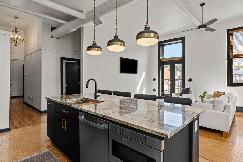 3080 Smallman Street, Unit 8 Pittsburgh, PA 15201 - Photo 16 of 39 a kitchen with stainless steel appliances granite countertop a stove a sink dishwasher and white cabinets with wooden floor