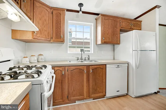 a kitchen with stainless steel appliances granite countertop a refrigerator a sink dishwasher a stove with wooden cabinets and floor