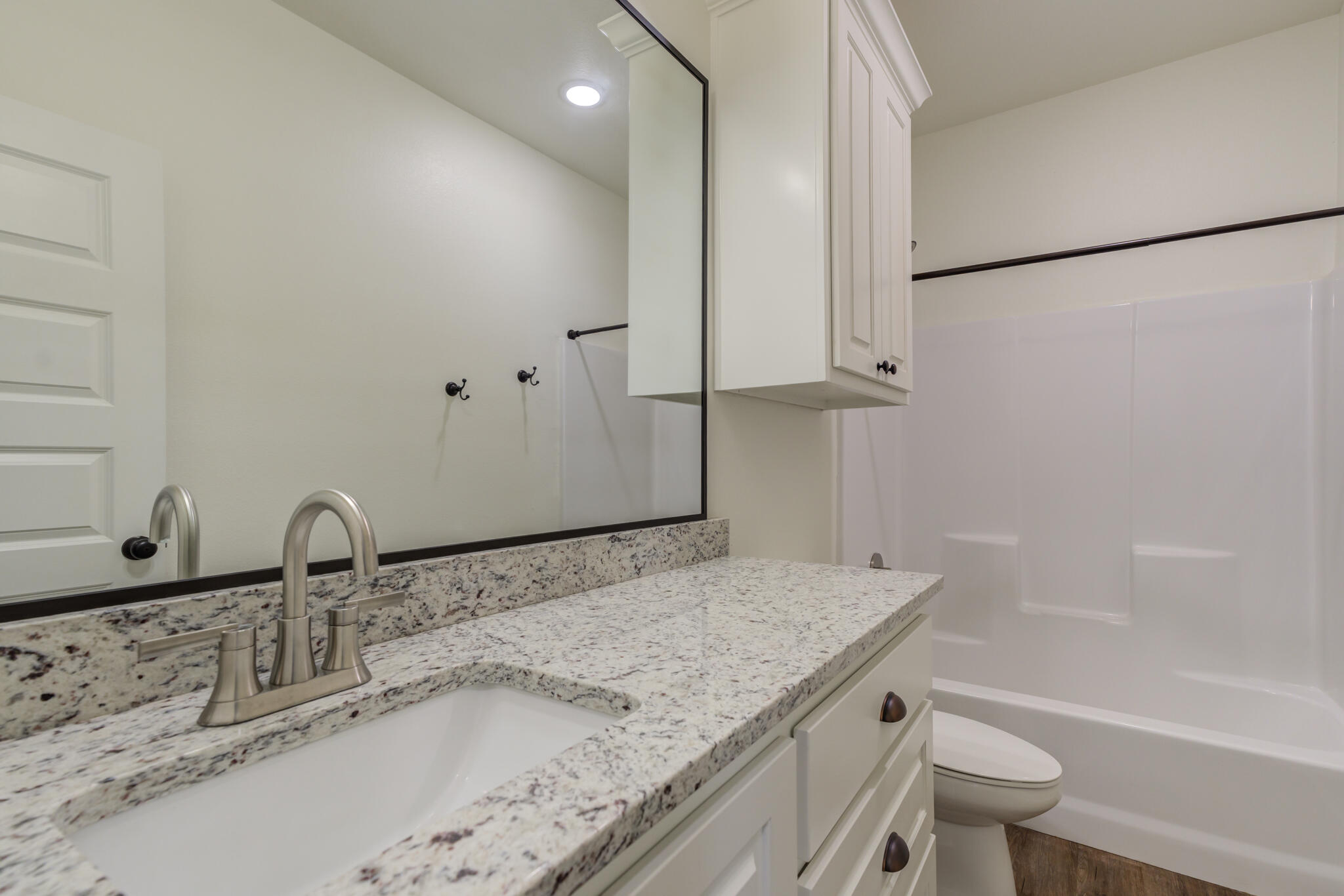 6908 55th Street Lubbock, TX 79407 - Photo 11 of 42 a bathroom with a granite countertop sink toilet and a mirror