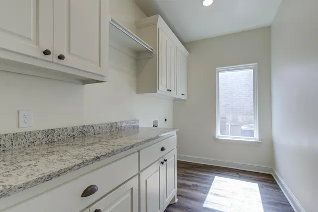 a kitchen with granite countertop white cabinets and window
