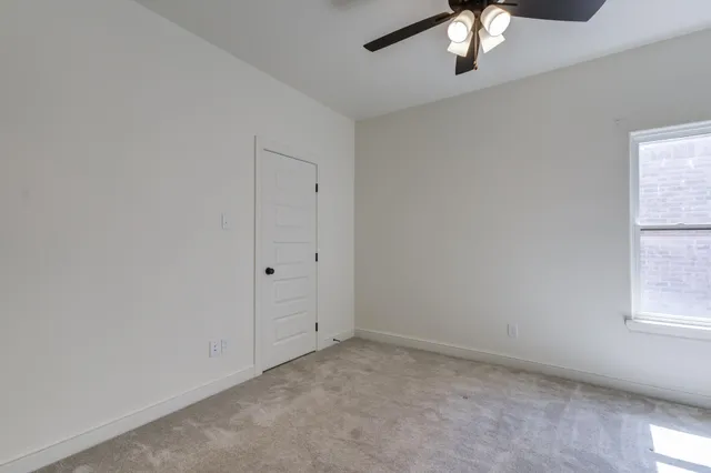an empty room with a chandelier fan and windows