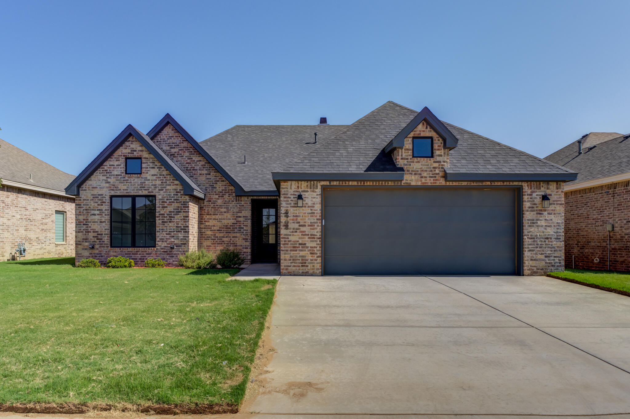6908 55th Street Lubbock, TX 79407 - Photo 2 of 42 a front view of a house with a yard and garage