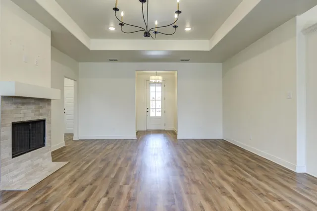 a view of an empty room with wooden floor fireplace and a window
