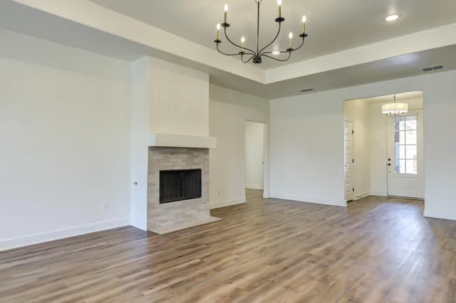 a view of an empty room with wooden floor and a fireplace