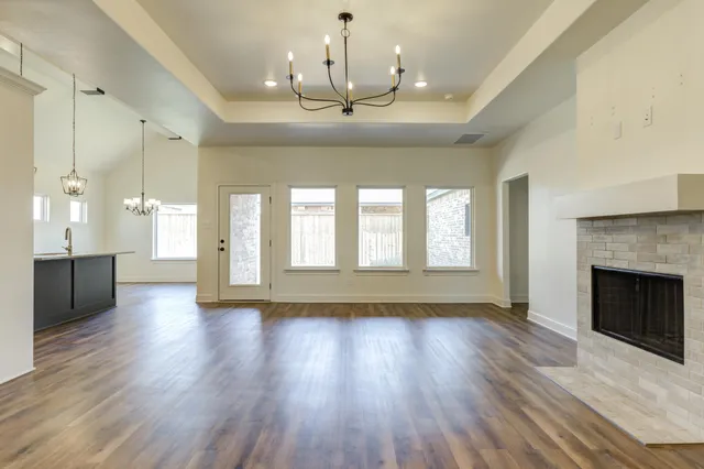 a view of an empty room with wooden floor and a fireplace