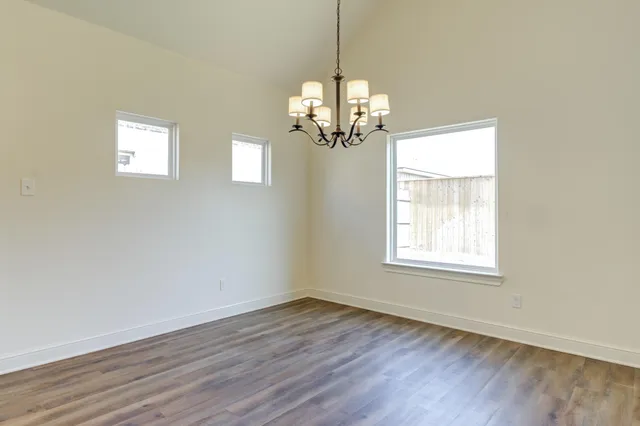 a view of a room with wooden floor chandelier and windows
