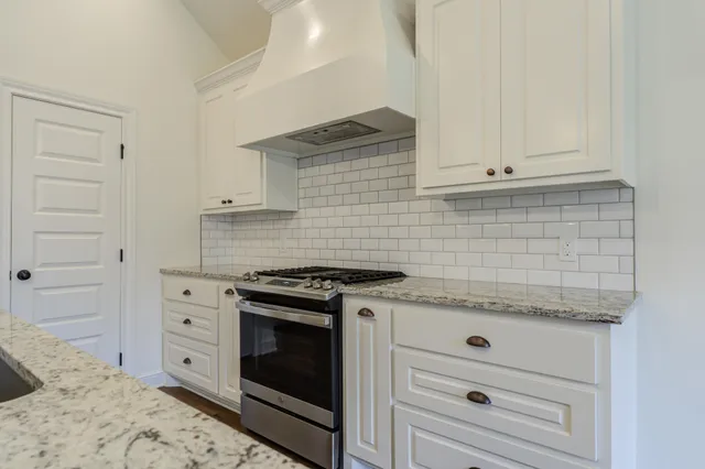 a kitchen with granite countertop white cabinets and white stove