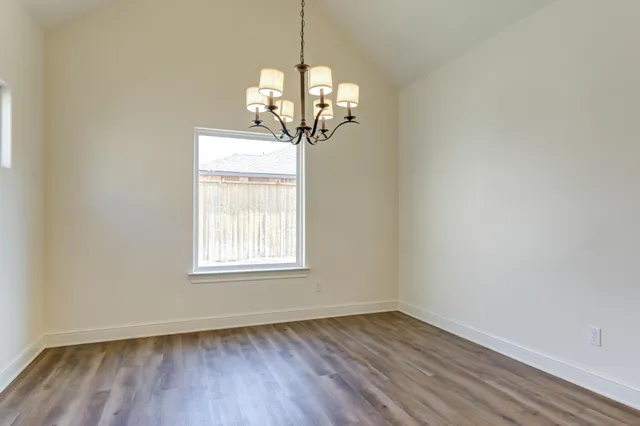 an empty room with wooden floor windows and entrance