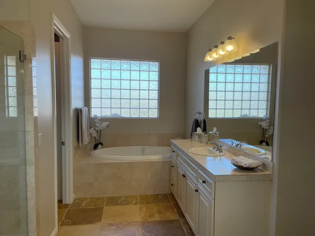 a bathroom with a tub sink shower and a mirror