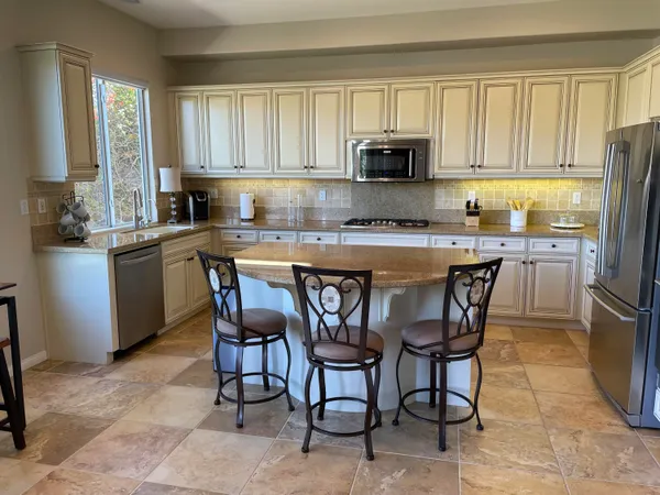 a kitchen with stainless steel appliances granite countertop a table chairs microwave and sink