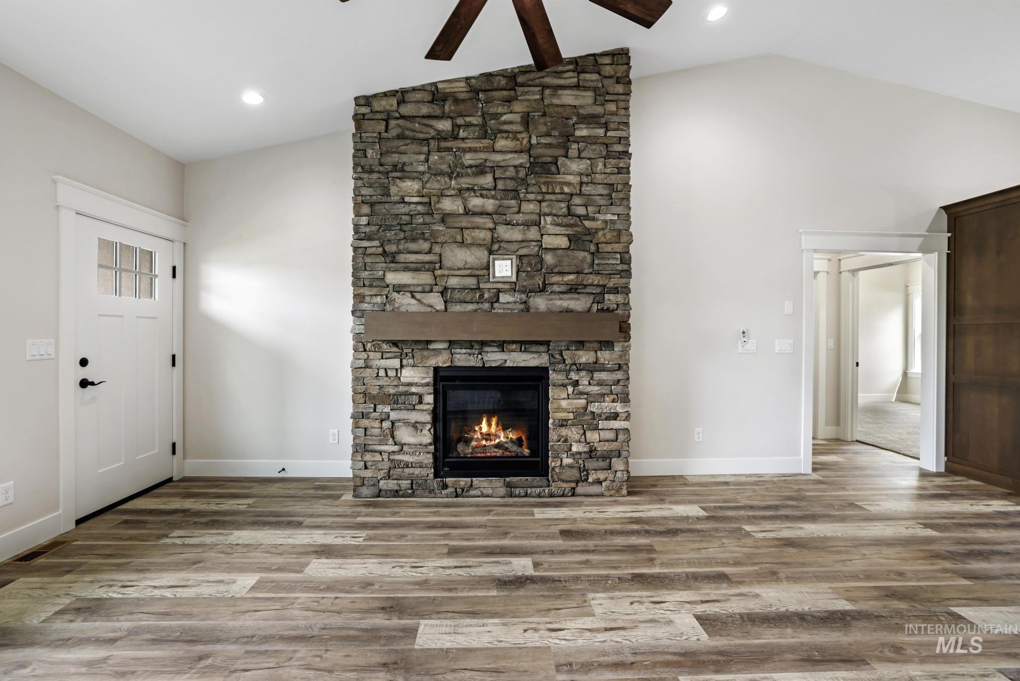 1413 Haizlee Way Twin Falls, ID 83301 - Photo 10 of 28 Unfurnished living room featuring wood finished floors, a stone fireplace, ceiling fan, recessed lighting, and high vaulted ceiling