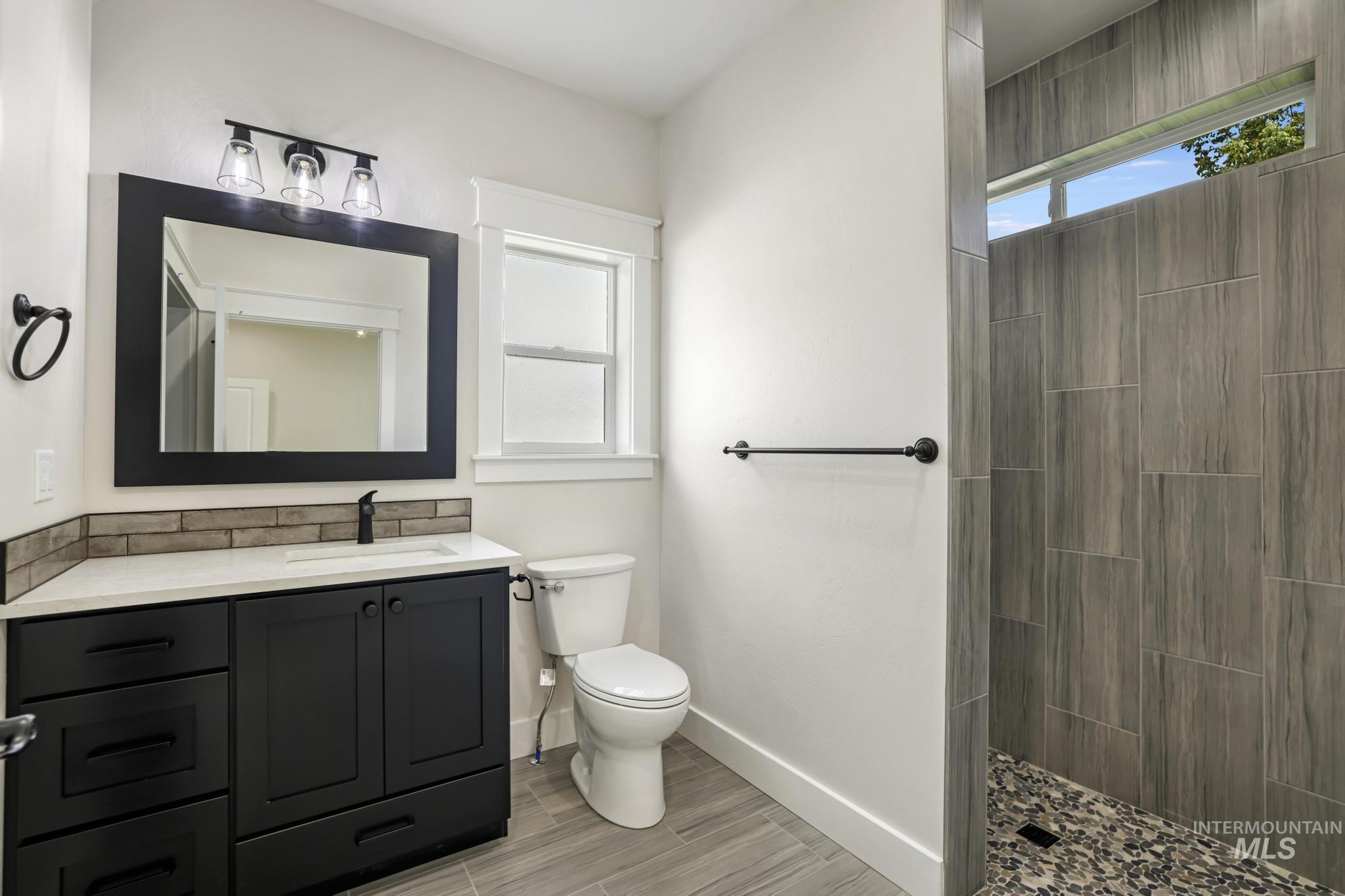 1413 Haizlee Way Twin Falls, ID 83301 - Photo 14 of 28 Bathroom with tiled shower, vanity, and wood tiled floors